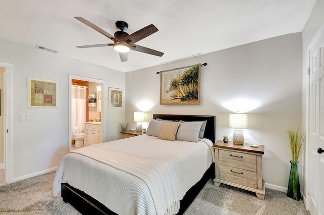 carpeted bedroom with ceiling fan and ensuite bath