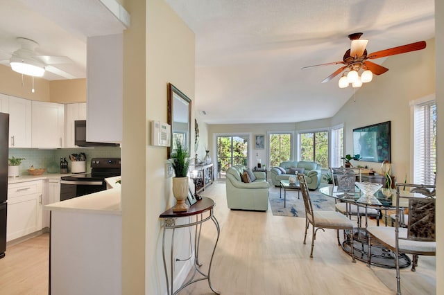 kitchen with black appliances, white cabinets, backsplash, ceiling fan, and light hardwood / wood-style floors