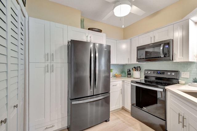 kitchen with backsplash, stainless steel appliances, light hardwood / wood-style flooring, and white cabinets