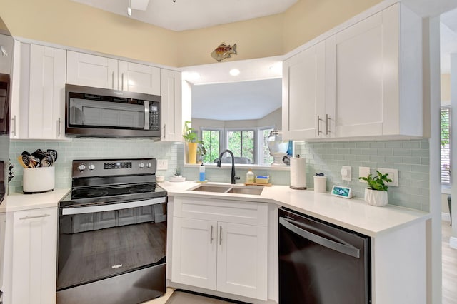 kitchen featuring range with electric stovetop, black dishwasher, sink, white cabinets, and backsplash