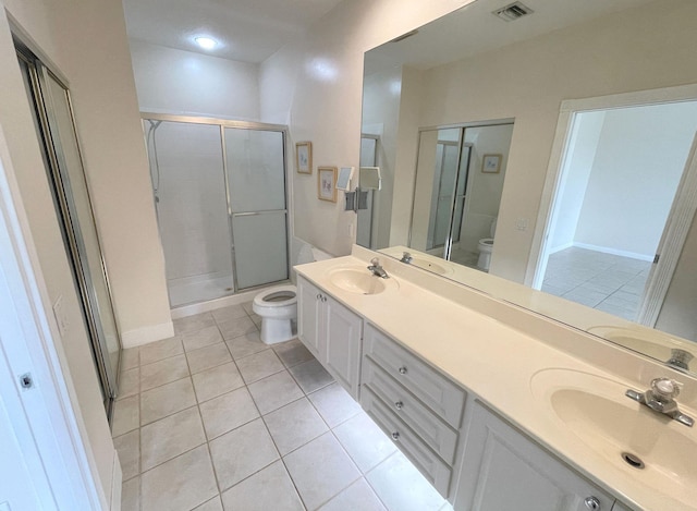 bathroom with tile patterned flooring, vanity, toilet, and a shower with door