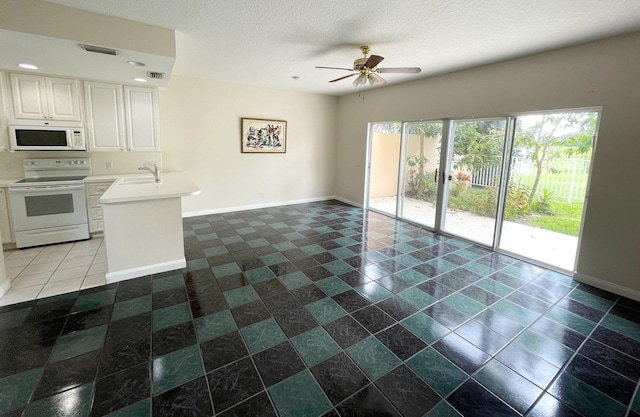 kitchen with kitchen peninsula, white appliances, ceiling fan, sink, and white cabinets