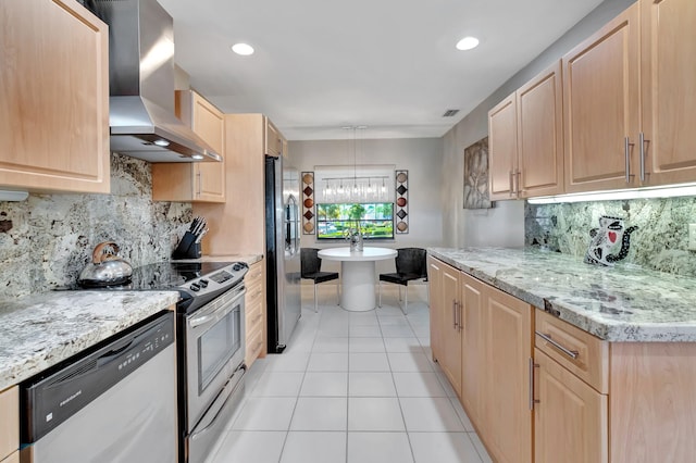 kitchen featuring light brown cabinets, light tile patterned floors, wall chimney range hood, and appliances with stainless steel finishes