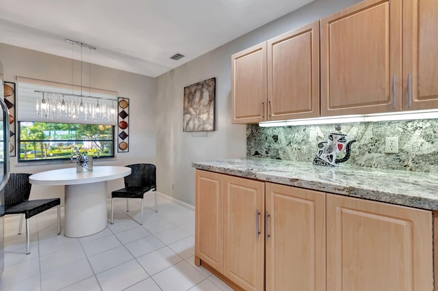 kitchen featuring decorative light fixtures, light tile patterned flooring, backsplash, and light brown cabinetry