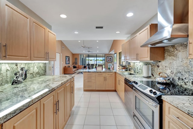 kitchen featuring kitchen peninsula, backsplash, stainless steel appliances, wall chimney range hood, and light brown cabinets