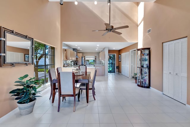 tiled dining space featuring ceiling fan, a high ceiling, and a wealth of natural light