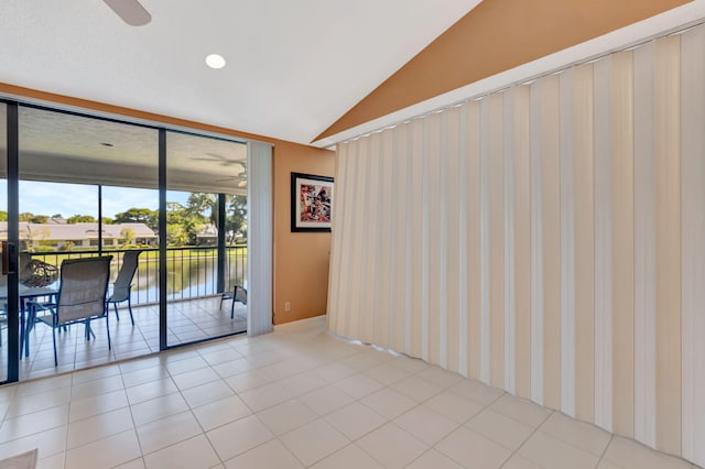 empty room with light tile patterned flooring, a water view, and vaulted ceiling