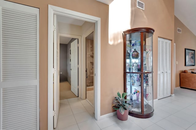 corridor featuring vaulted ceiling and light tile patterned flooring