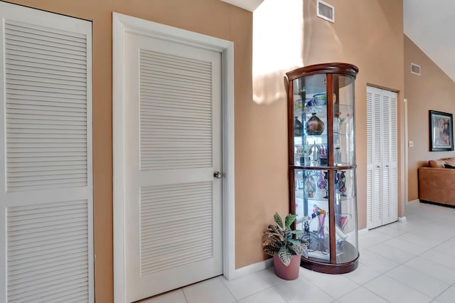 doorway featuring lofted ceiling and light tile patterned flooring