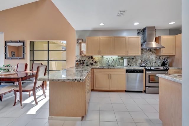 kitchen featuring kitchen peninsula, light brown cabinets, wall chimney exhaust hood, and appliances with stainless steel finishes