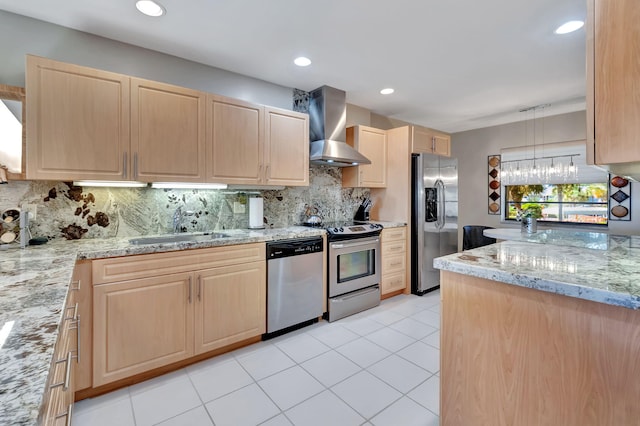 kitchen with appliances with stainless steel finishes, light brown cabinetry, tasteful backsplash, wall chimney exhaust hood, and pendant lighting