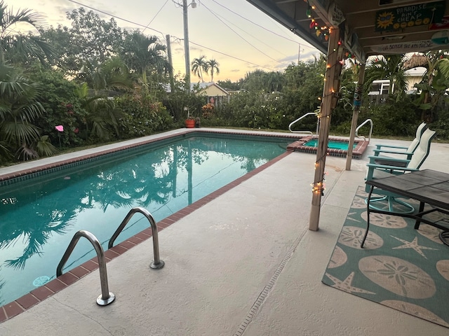 pool at dusk featuring a patio area