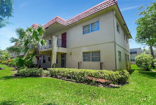 rear view of property featuring a lawn and a balcony