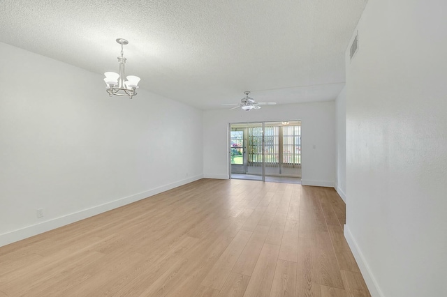 spare room featuring visible vents, baseboards, a textured ceiling, light wood-type flooring, and ceiling fan with notable chandelier