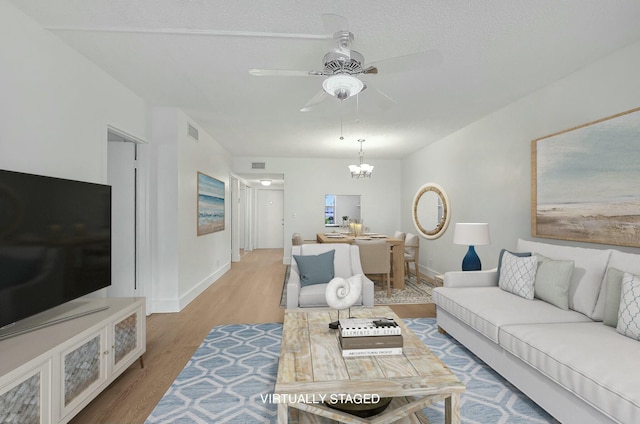 living room with baseboards, visible vents, wood finished floors, and ceiling fan with notable chandelier