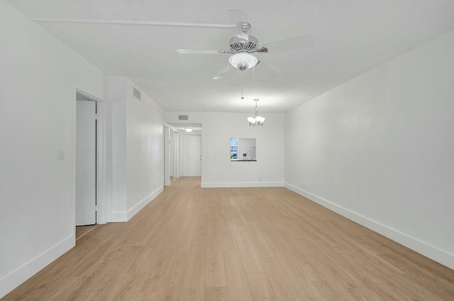 unfurnished room with light wood-style flooring, visible vents, baseboards, and ceiling fan with notable chandelier