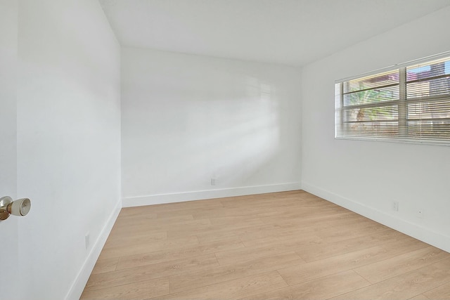 spare room featuring light wood-type flooring and baseboards