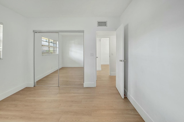 unfurnished bedroom featuring a closet, light wood-type flooring, visible vents, and baseboards