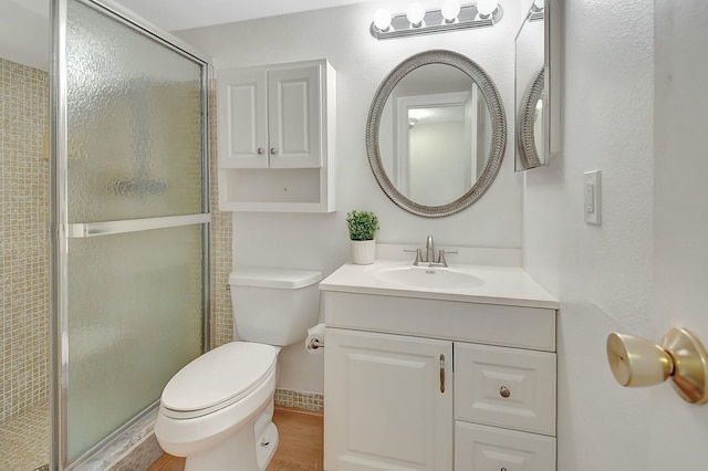 bathroom featuring vanity, wood finished floors, a shower stall, and toilet