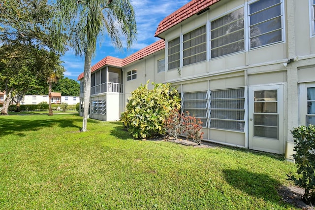 back of house with a yard and a tile roof