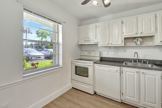 kitchen with white appliances, white cabinets, dark countertops, under cabinet range hood, and a sink