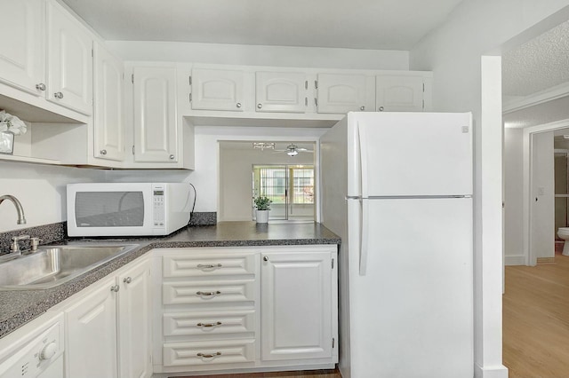 kitchen featuring white appliances, white cabinets, and a sink