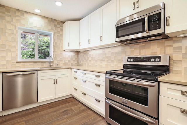 kitchen featuring appliances with stainless steel finishes, dark hardwood / wood-style flooring, backsplash, sink, and white cabinets