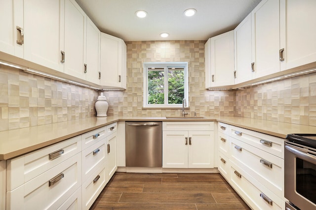 kitchen with appliances with stainless steel finishes, white cabinetry, dark wood-type flooring, and sink