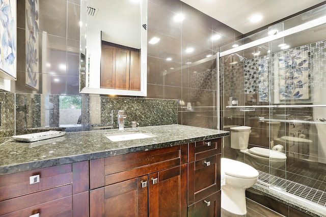 bathroom with an enclosed shower, vanity, toilet, and tasteful backsplash