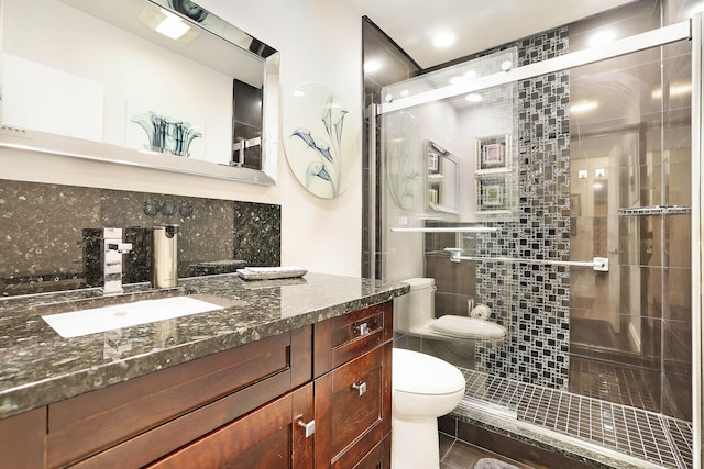 bathroom with decorative backsplash, vanity, toilet, and a shower with door