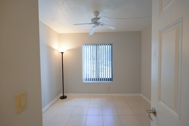 tiled empty room featuring ceiling fan and a textured ceiling