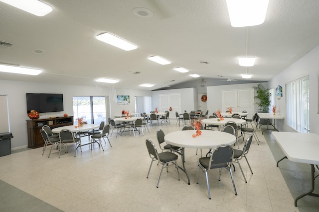 dining space featuring a textured ceiling and vaulted ceiling