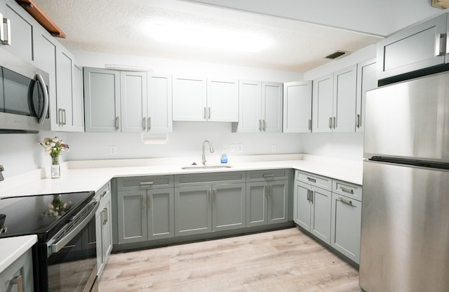 kitchen featuring gray cabinetry, sink, light wood-type flooring, and stainless steel appliances