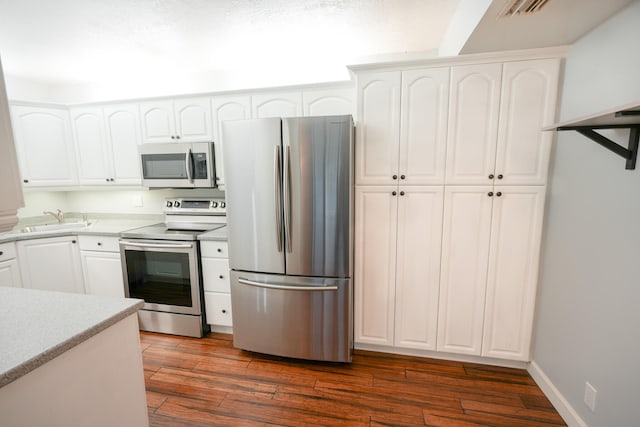 kitchen with dark hardwood / wood-style flooring, white cabinetry, and stainless steel appliances