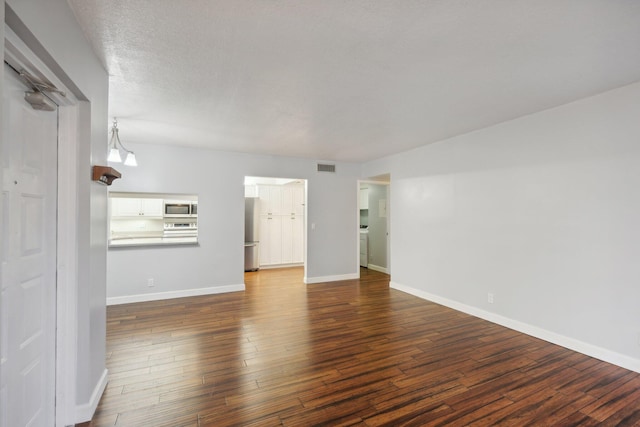 unfurnished living room with a textured ceiling and dark hardwood / wood-style floors