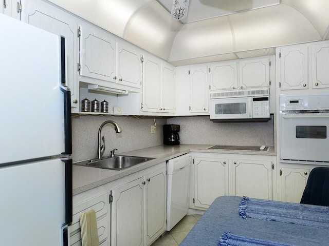 kitchen with white cabinets, light tile patterned floors, white appliances, and sink