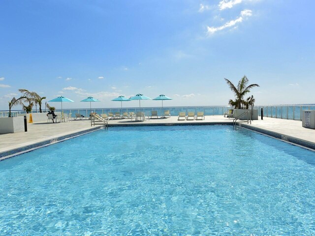 view of pool featuring a water view and a patio