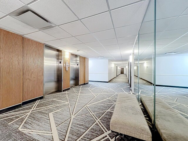 interior space featuring carpet, a paneled ceiling, and elevator