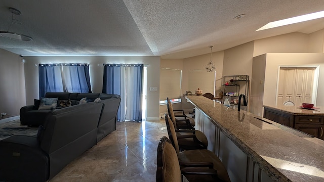 interior space featuring lofted ceiling with skylight, sink, and a textured ceiling