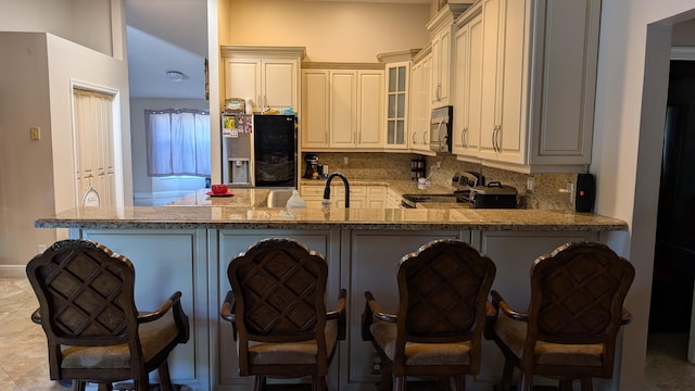 kitchen with sink, a breakfast bar area, tasteful backsplash, kitchen peninsula, and stainless steel appliances