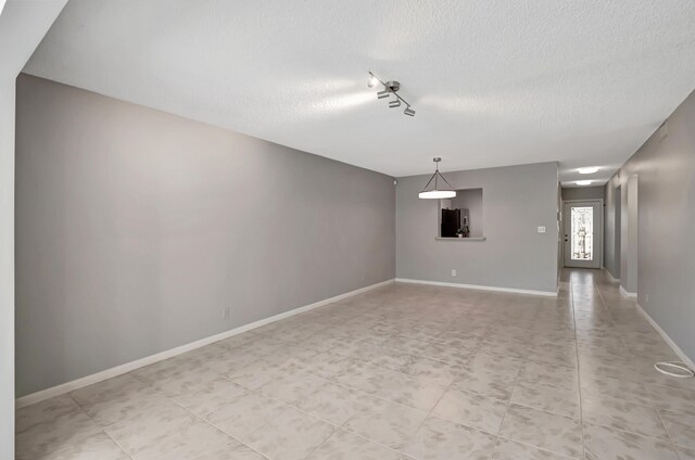 unfurnished living room featuring rail lighting and a textured ceiling