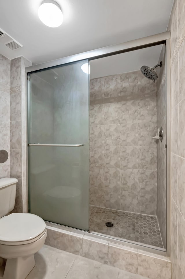 bathroom with tile patterned floors, a shower with door, and toilet