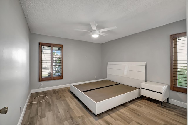 unfurnished bedroom with hardwood / wood-style flooring, ceiling fan, and a textured ceiling