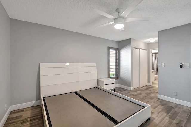 bedroom with ensuite bath, ceiling fan, hardwood / wood-style floors, and a textured ceiling