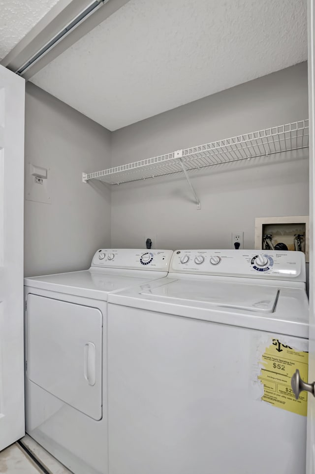 washroom with washer and clothes dryer and a textured ceiling