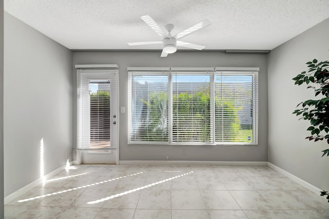 tiled empty room featuring a textured ceiling, ceiling fan, and a healthy amount of sunlight