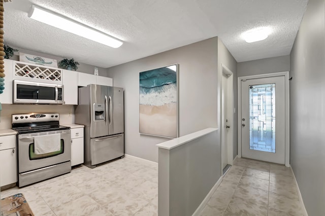 kitchen featuring appliances with stainless steel finishes, a textured ceiling, and white cabinetry