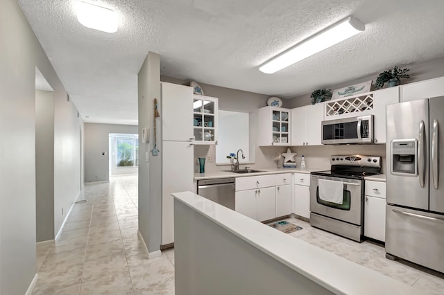 kitchen with sink, white cabinets, a textured ceiling, and appliances with stainless steel finishes