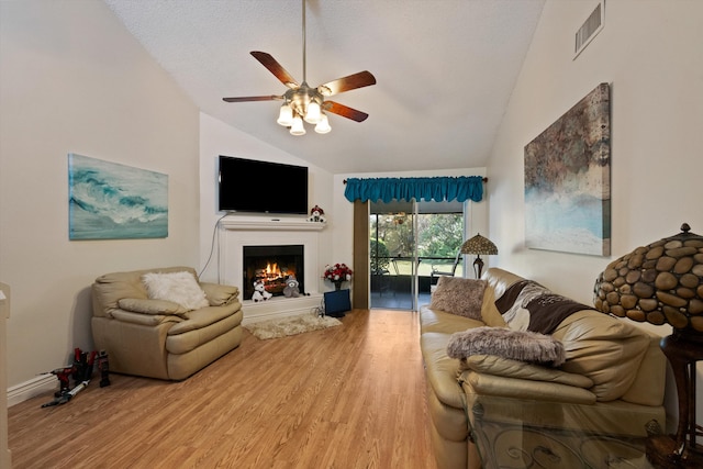 living room with a textured ceiling, light hardwood / wood-style floors, high vaulted ceiling, and ceiling fan