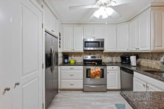 kitchen featuring white cabinetry, stainless steel appliances, light hardwood / wood-style flooring, backsplash, and dark stone countertops